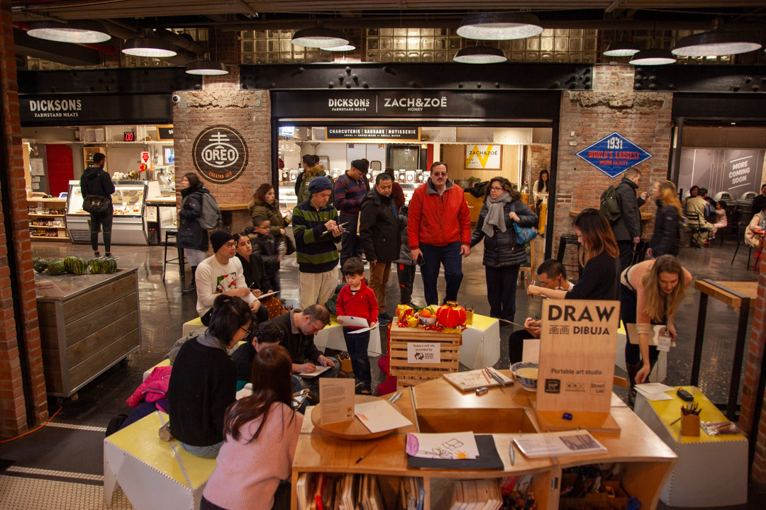 People sitting and drawing in an indoor market.
