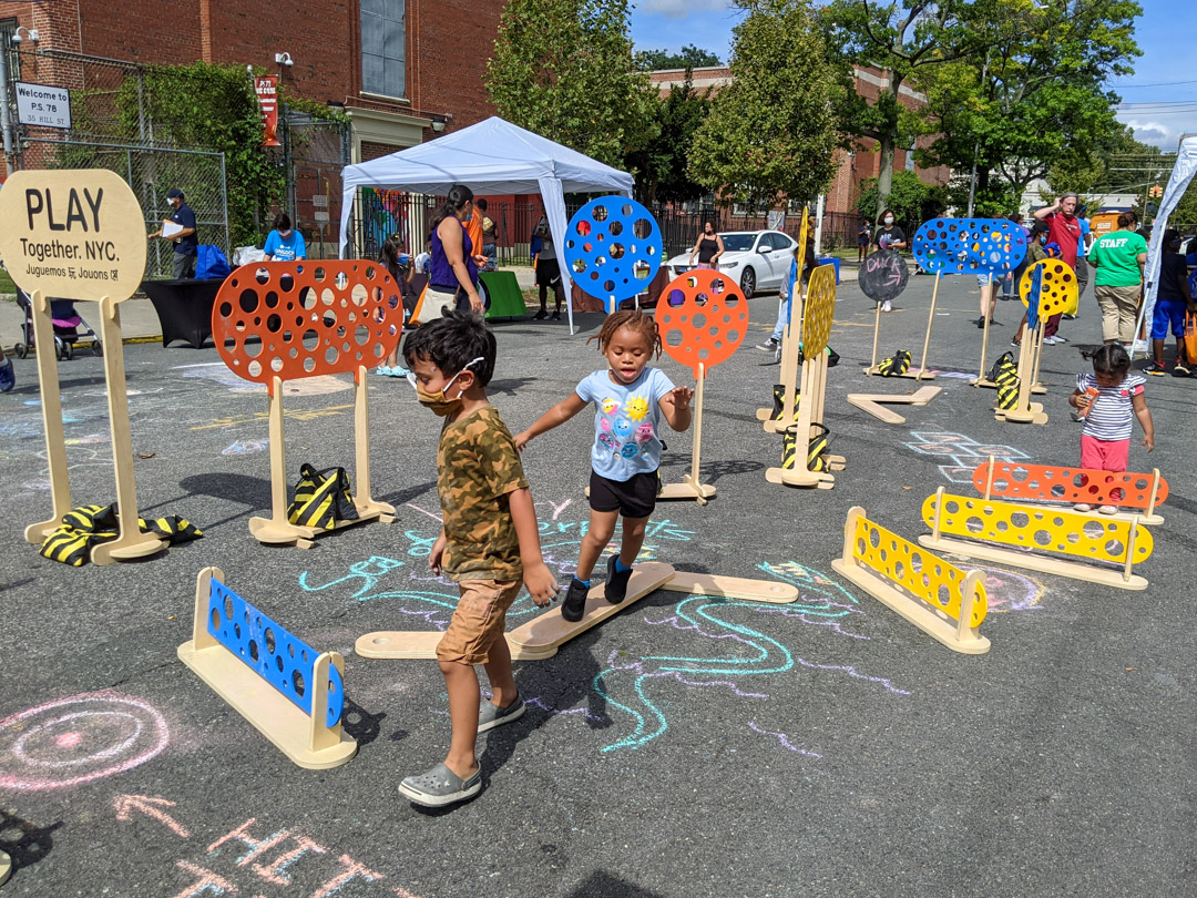 Children playing on the chalked street with colorful obstacle courses.