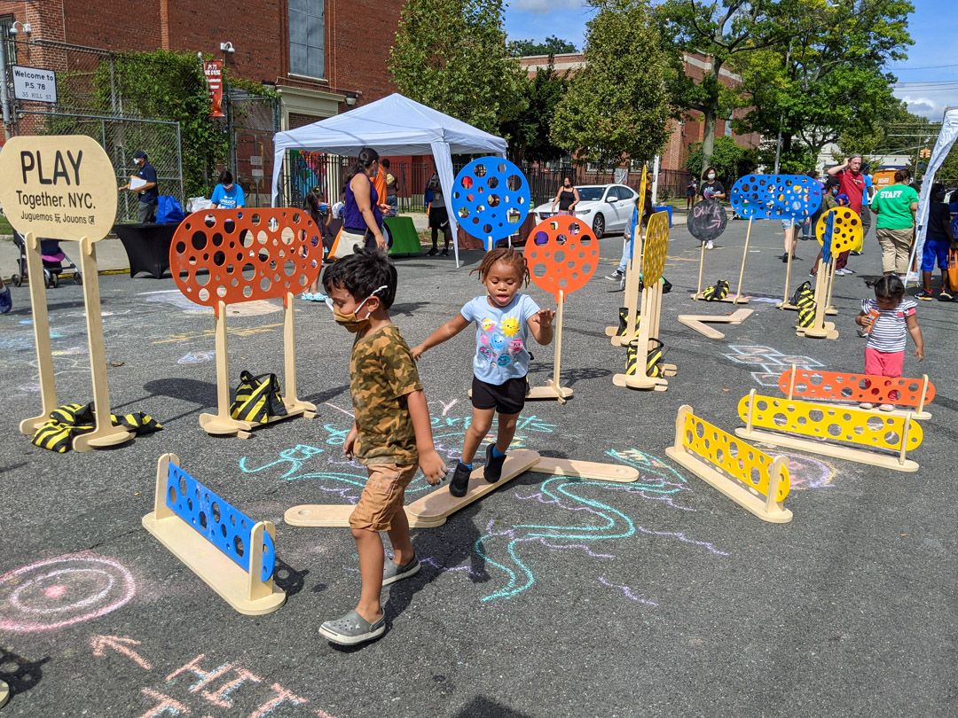 Children playing on the chalked street with colorful obstacle courses.