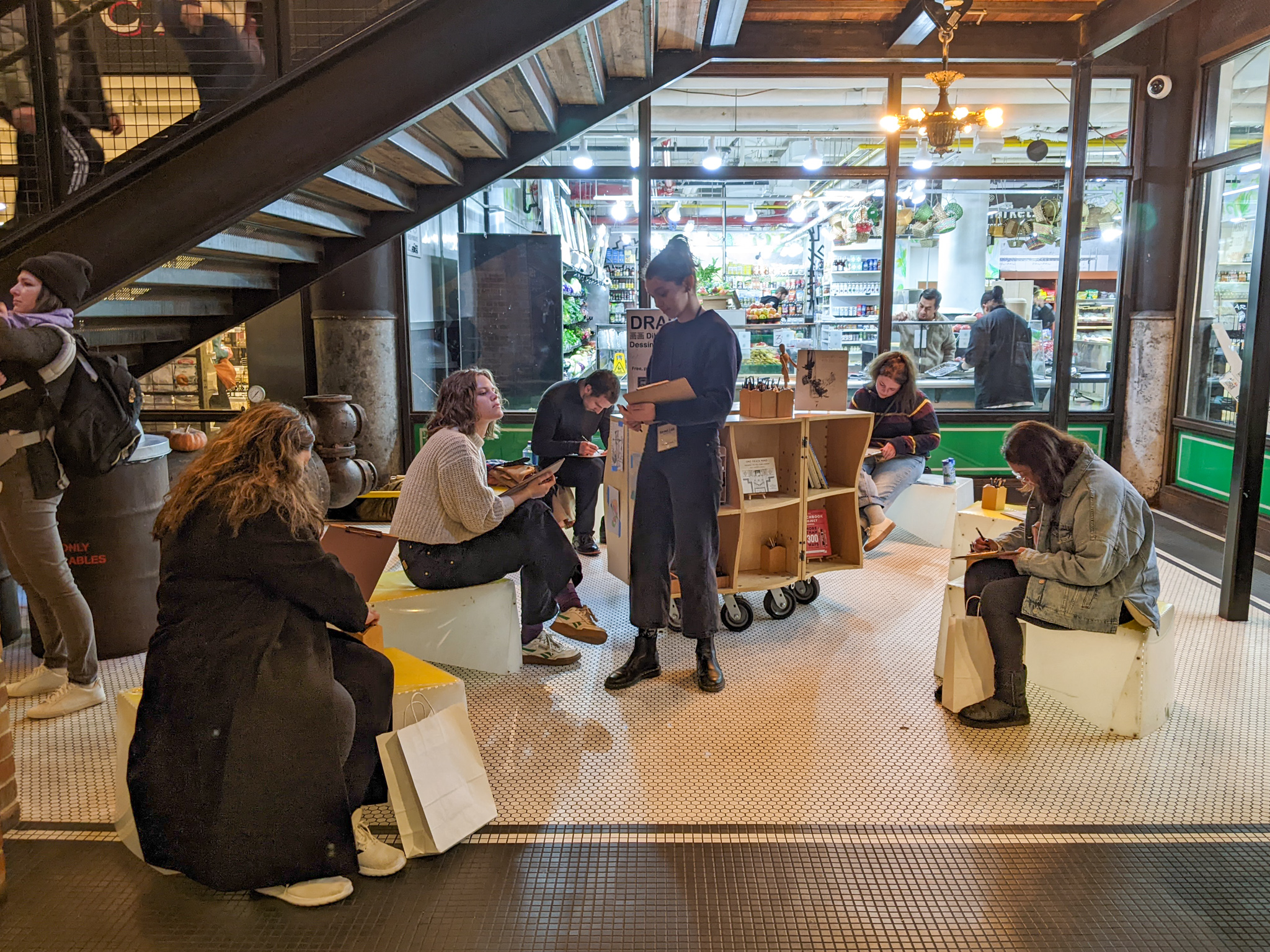 A view of people drawing in an indoor market.