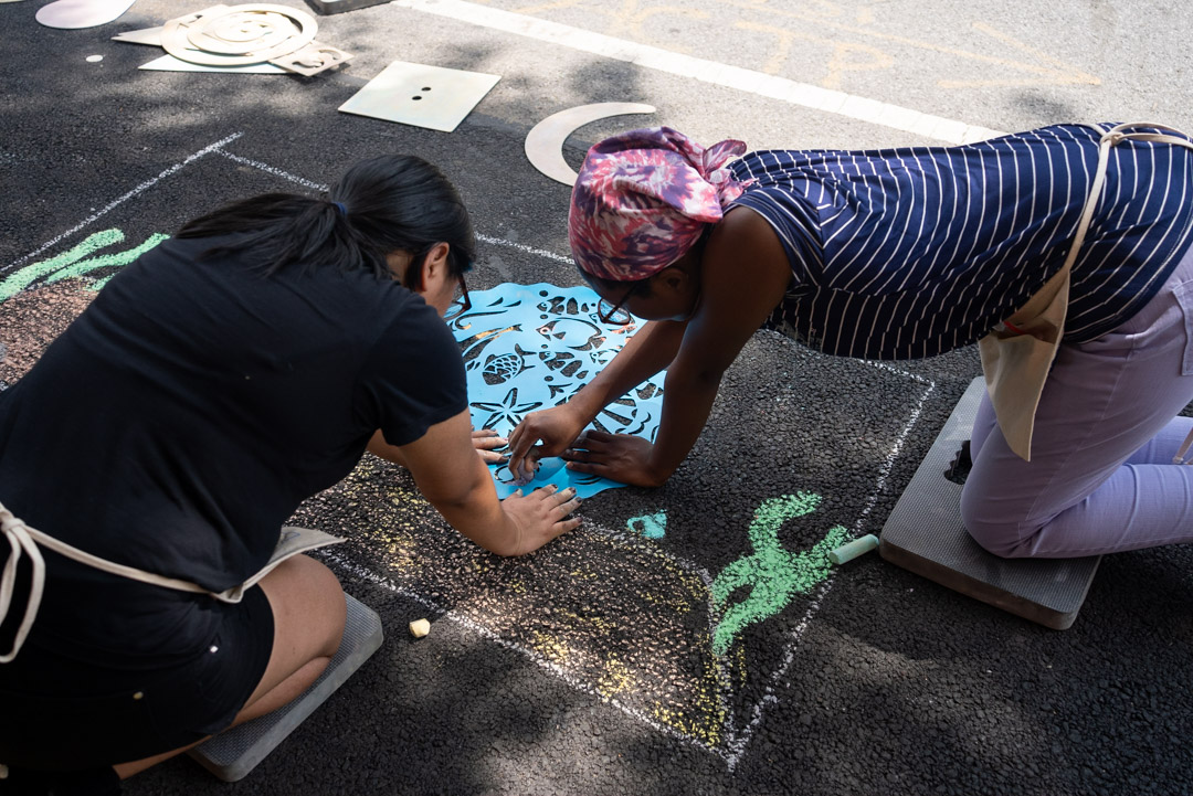 Two teenagers chalking on the ground.