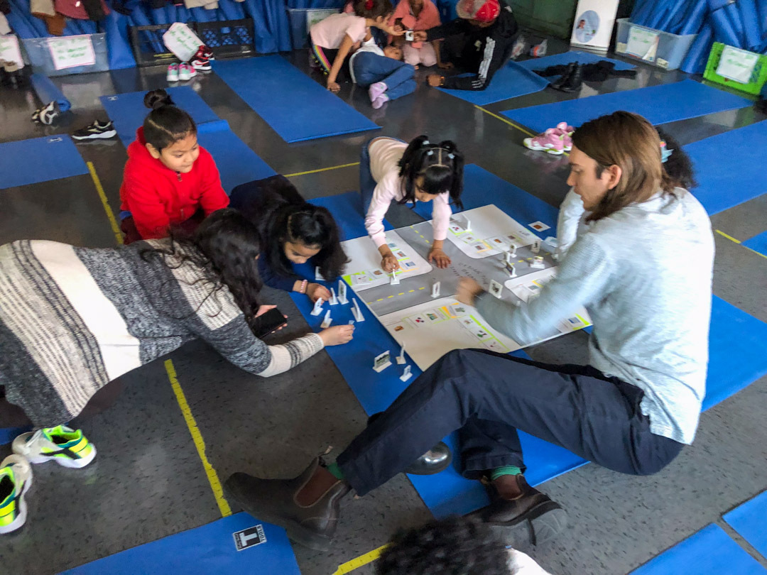 a teacher leading a group of elementary school students a workshop on reimagining our streets