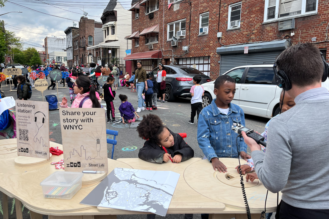 Elementary school students talking to a radio host on the street in NYC.