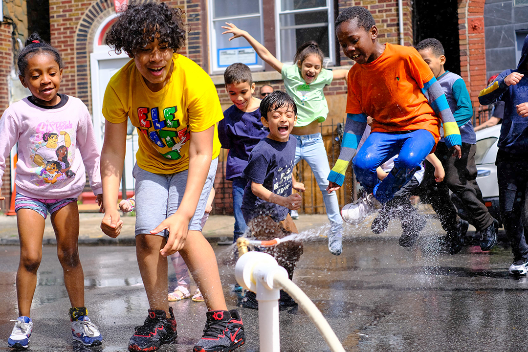 children playing with water coming out from fire hydrant attachment 