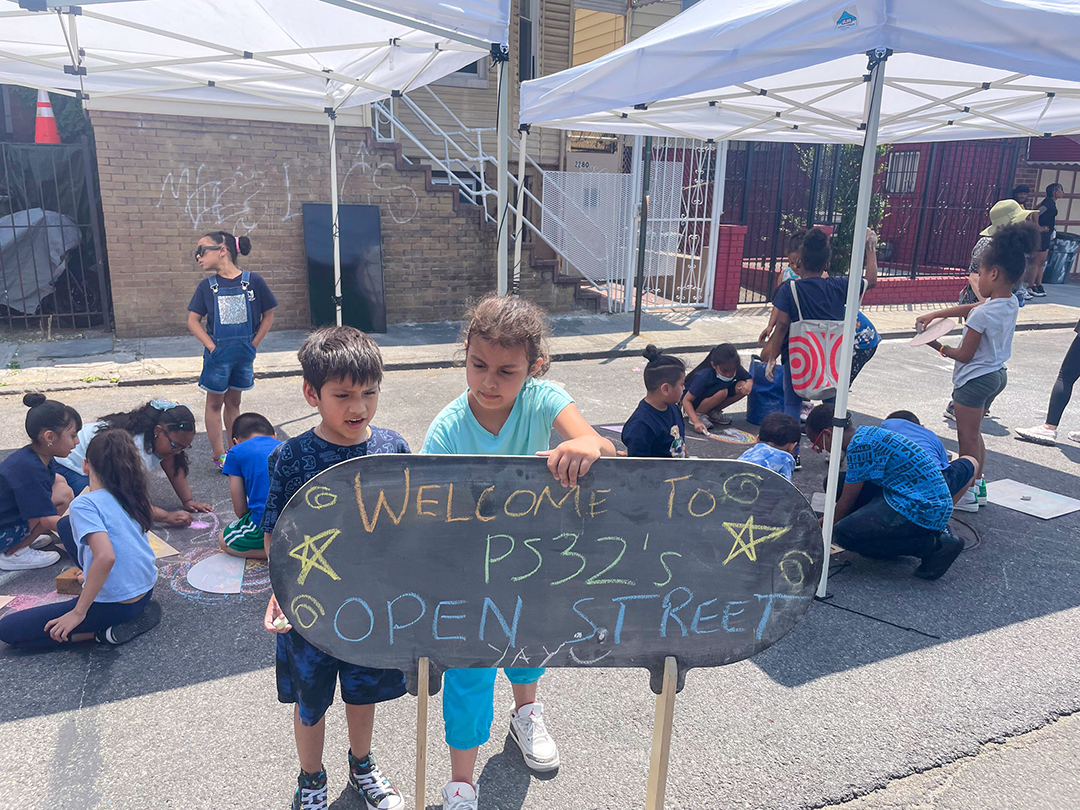 children on the street with the sign reading "Welcome to PS32's Open Street"