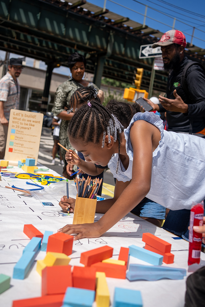 Group of people engaging in a community engagement activity. The signage reads "IMAGINE NYC E 234th St"