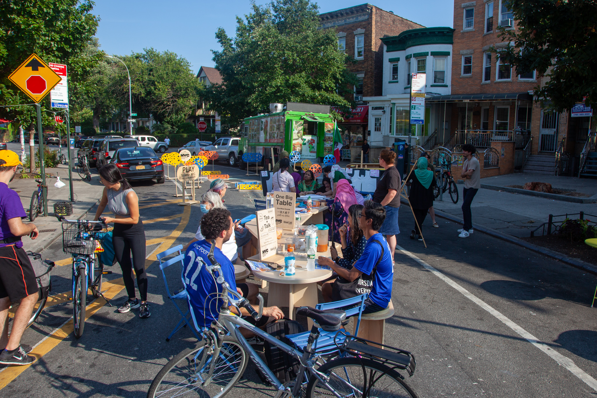19_2022-09-18-160510_beverleyrd_churchave-e2st_2048px People sitting down, eating, and drinking on an one big table on the street of NYC.