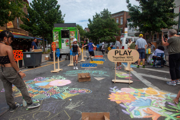 People chalking on the ground on a street in NYC.