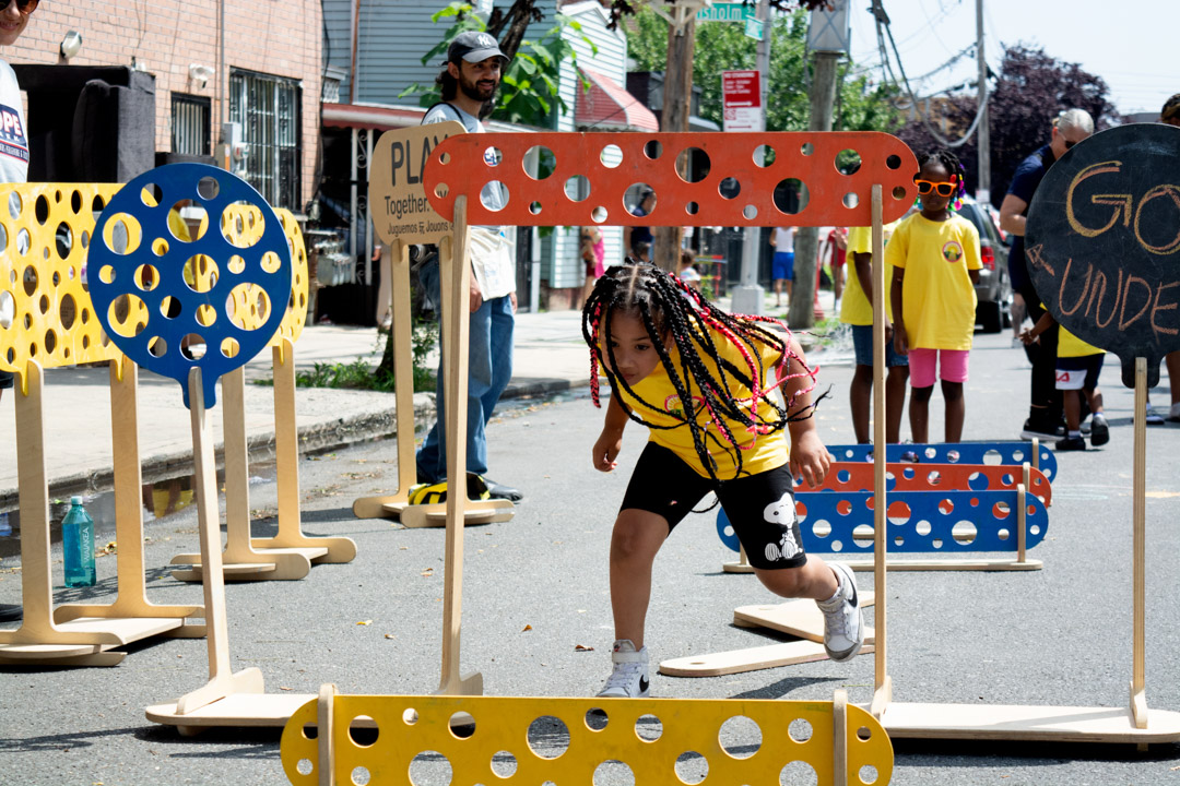 A girl jumping around an obstacle course on the street.