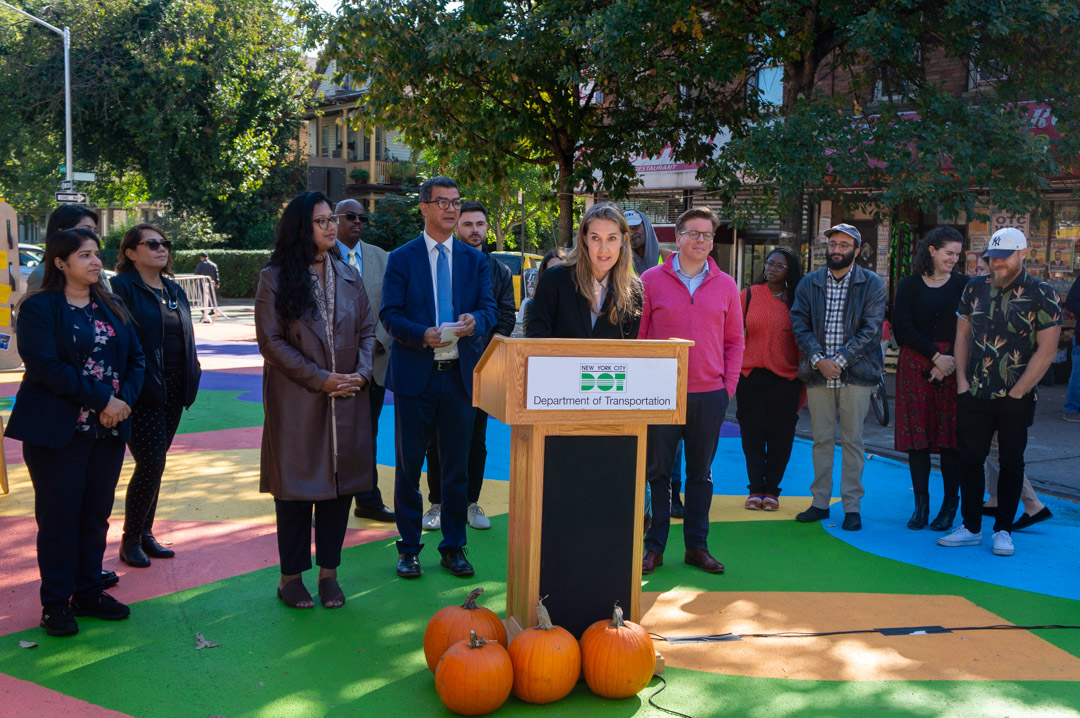 A woman speaking at a podium for a celebration of opening of a new plaza in NYC.