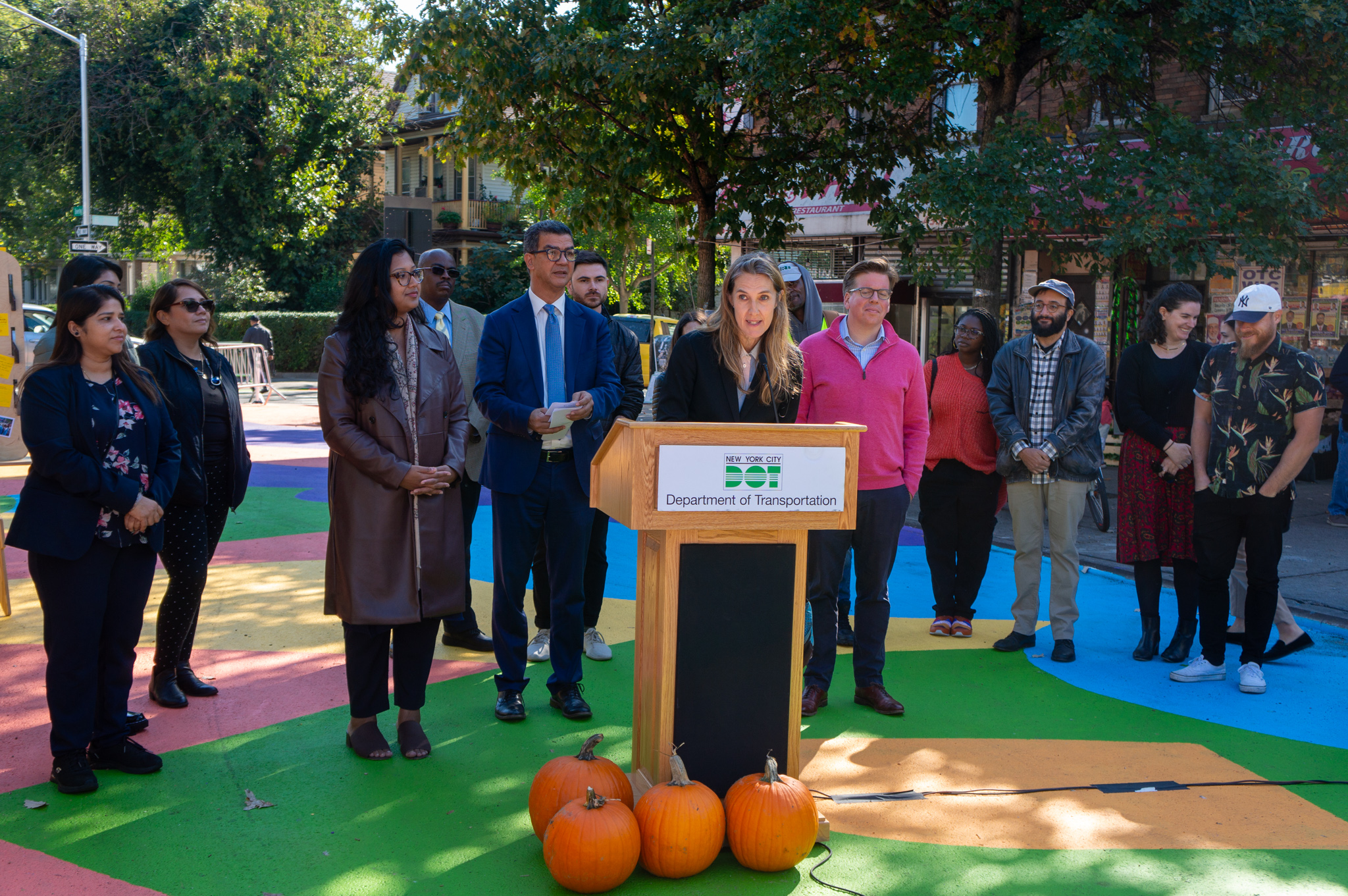 A woman speaking at a podium set up on the street.