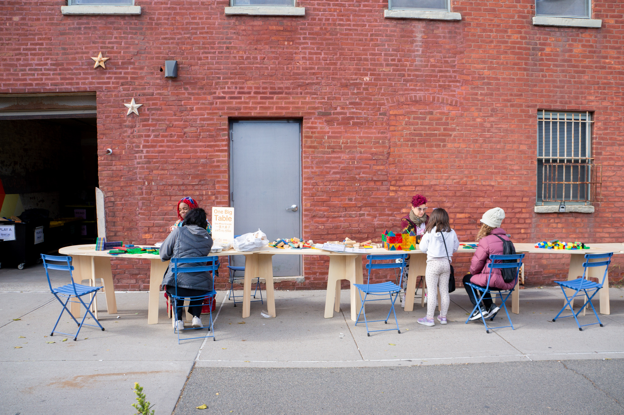 People sitting at a table on a sidewalk.