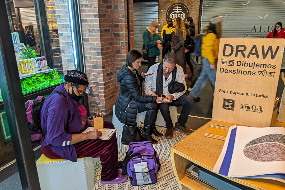 People sitting and drawing in an indoor market.