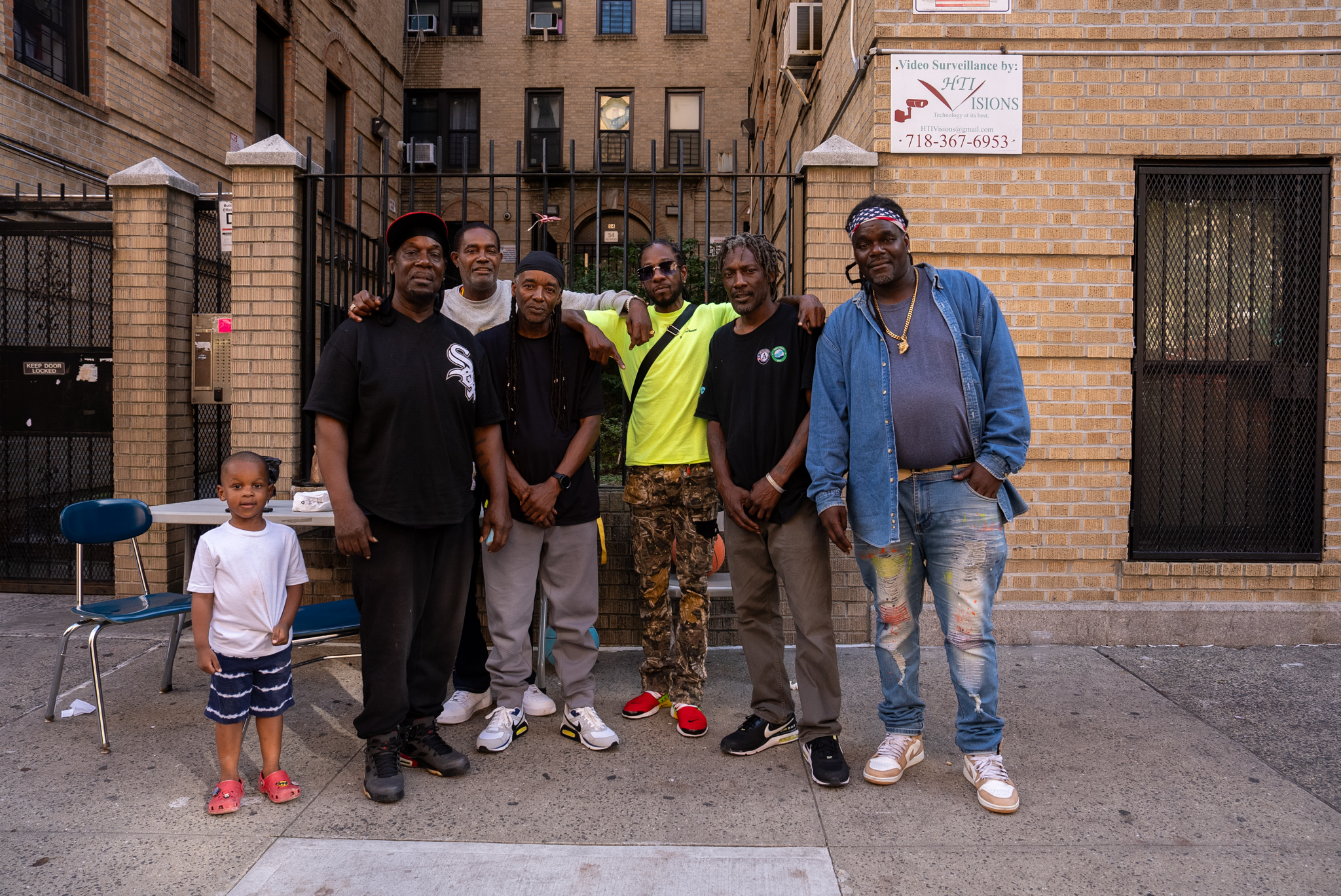 A group of Black men and a young boy posing in front of an apartment in New York City.