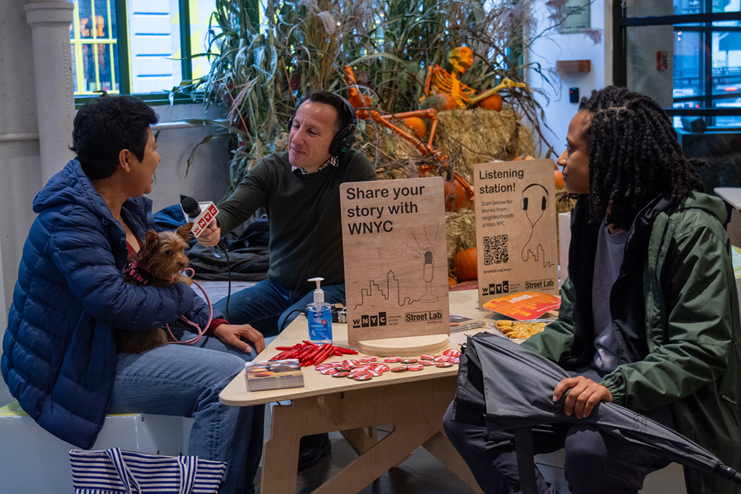 A radio host interviewing people in an indoor market.