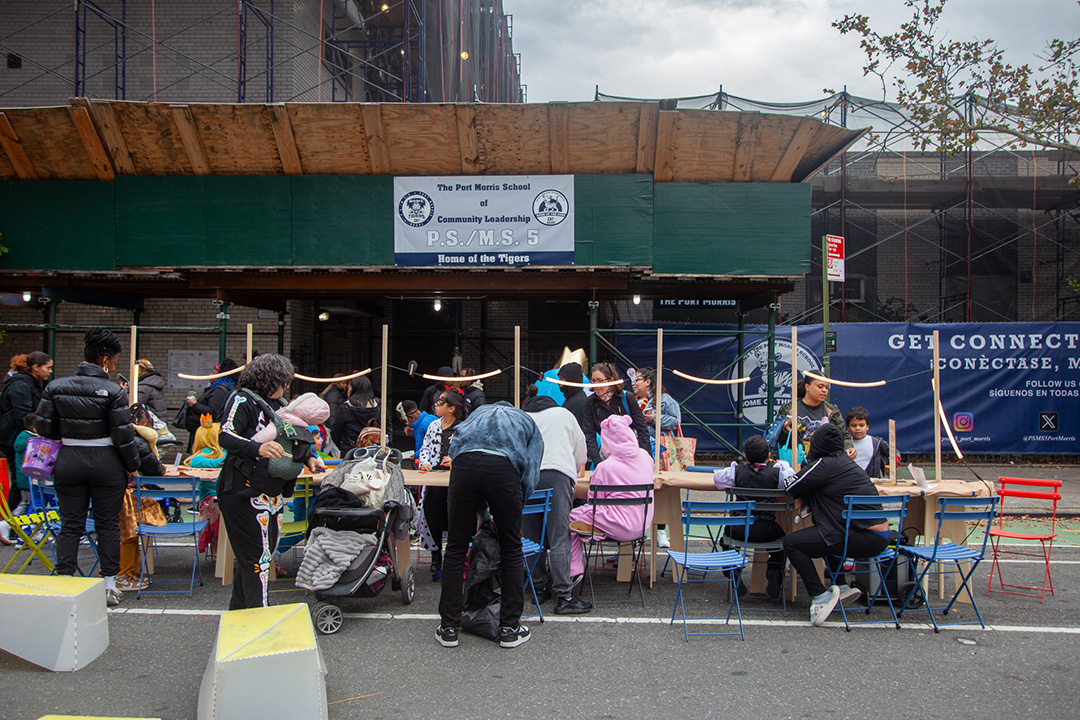 People drawing on an One Big Table by an organization Street Lab at an open street in NYC.