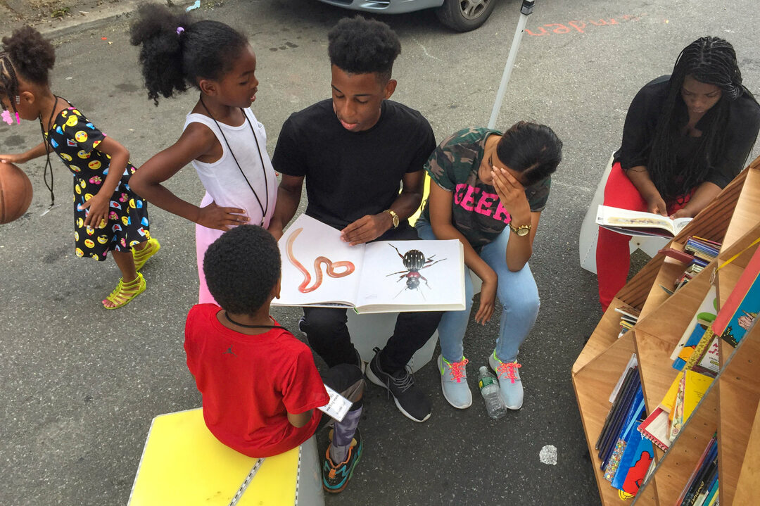 Teenagers and children looking (reading) a picture book together on the street of NYC.