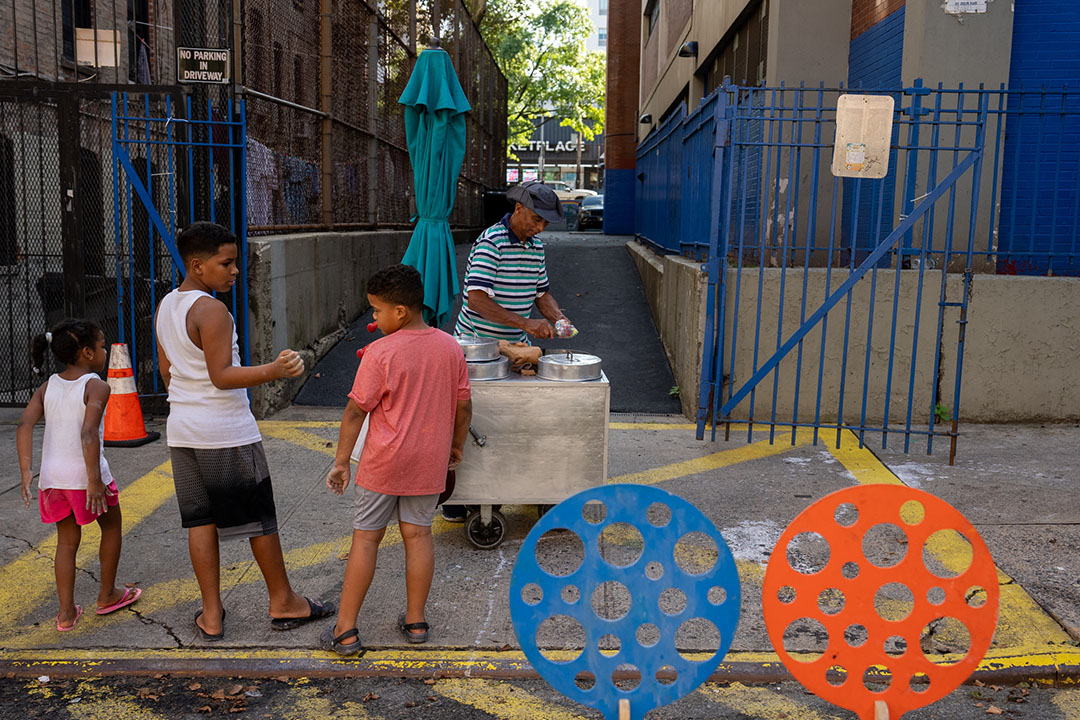 A view of children and an ice cream vendor on the street of NYC.