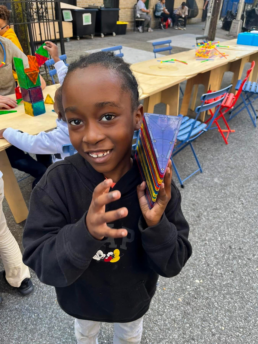 A smiling boy holding colorful magnatiles.