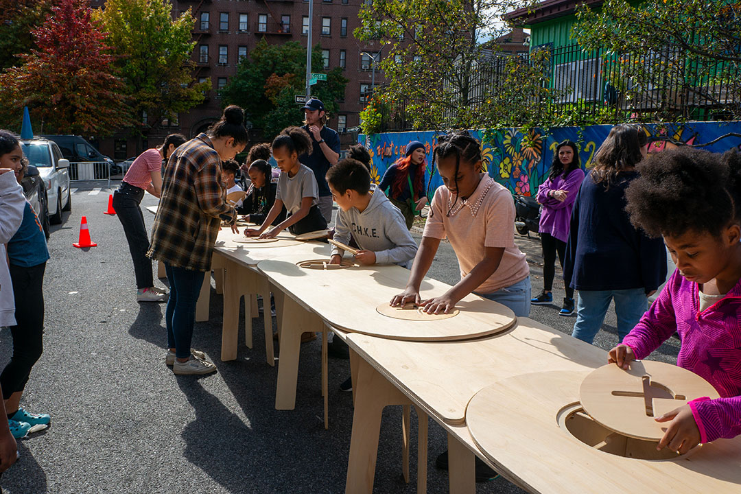 An elementary school students assembling a table on the street of NYC.