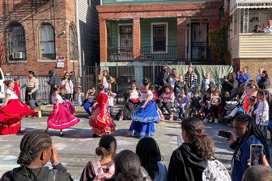 A group of teen performers dancing on the street of NYC.