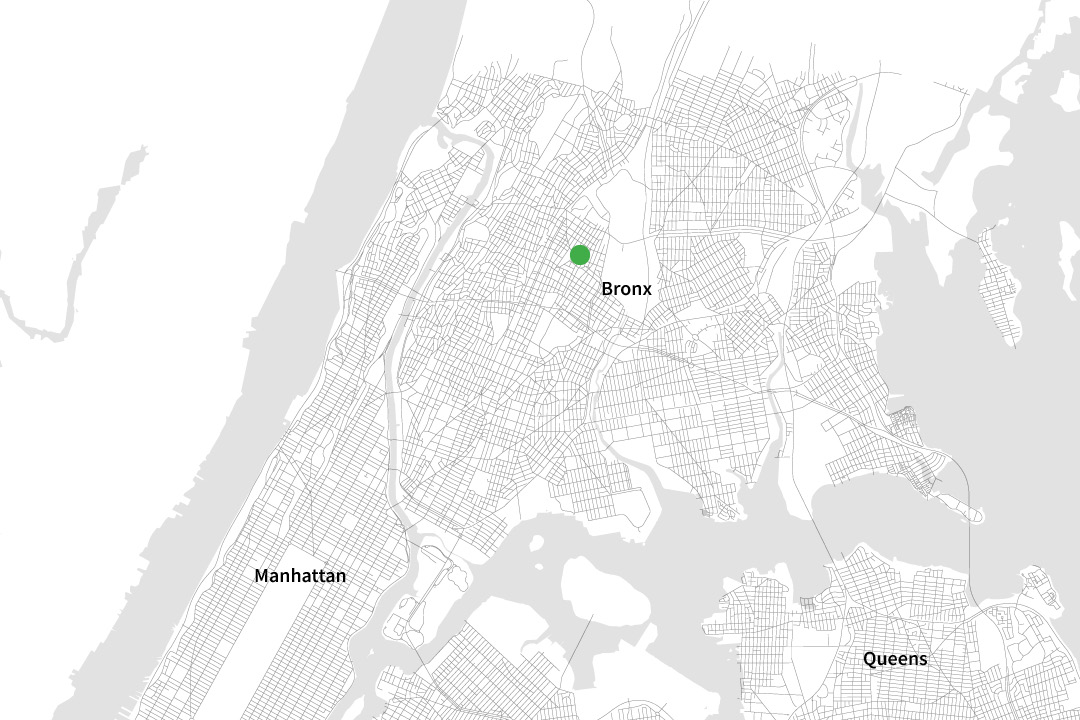 A black and white map of NYC zoomed in to only see some parts of the "Bronx," "Manhattan," and "Queens" with a green dot on a street in the Bronx.