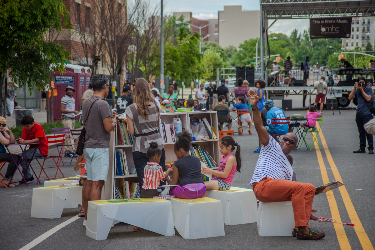 A car-free street with chalk murals and play obstacles on the ground.