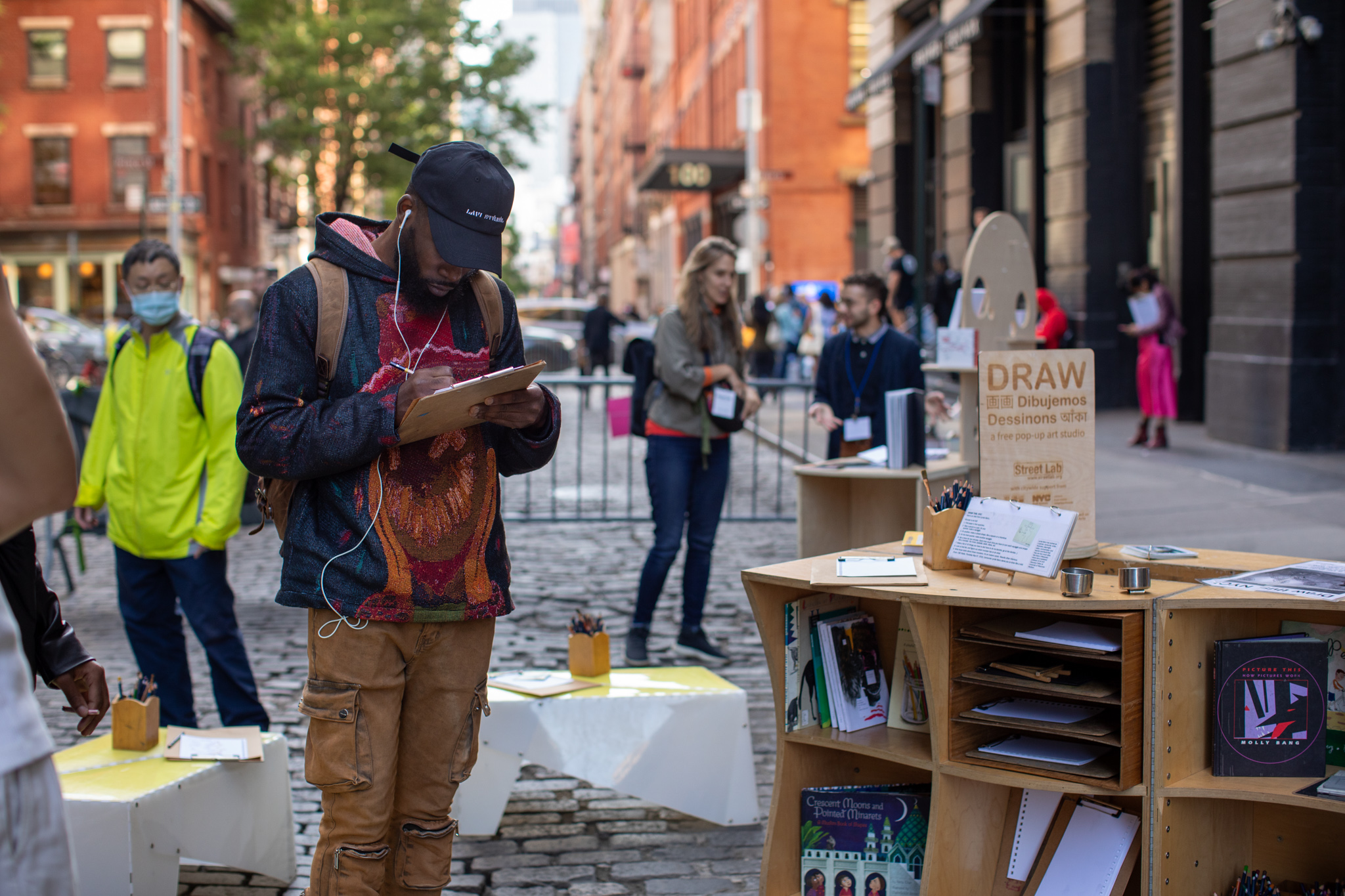 A man drawing on a clipboard standing on the street.