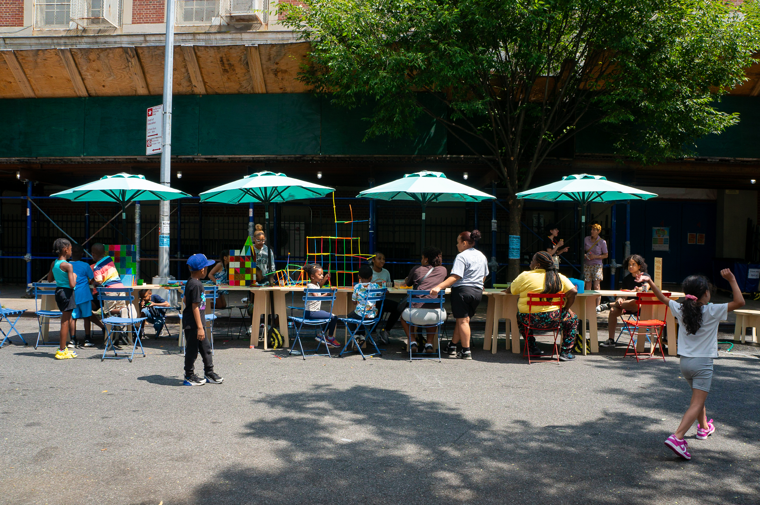 One big table on the street, with children playing with magnetiles and blocks.