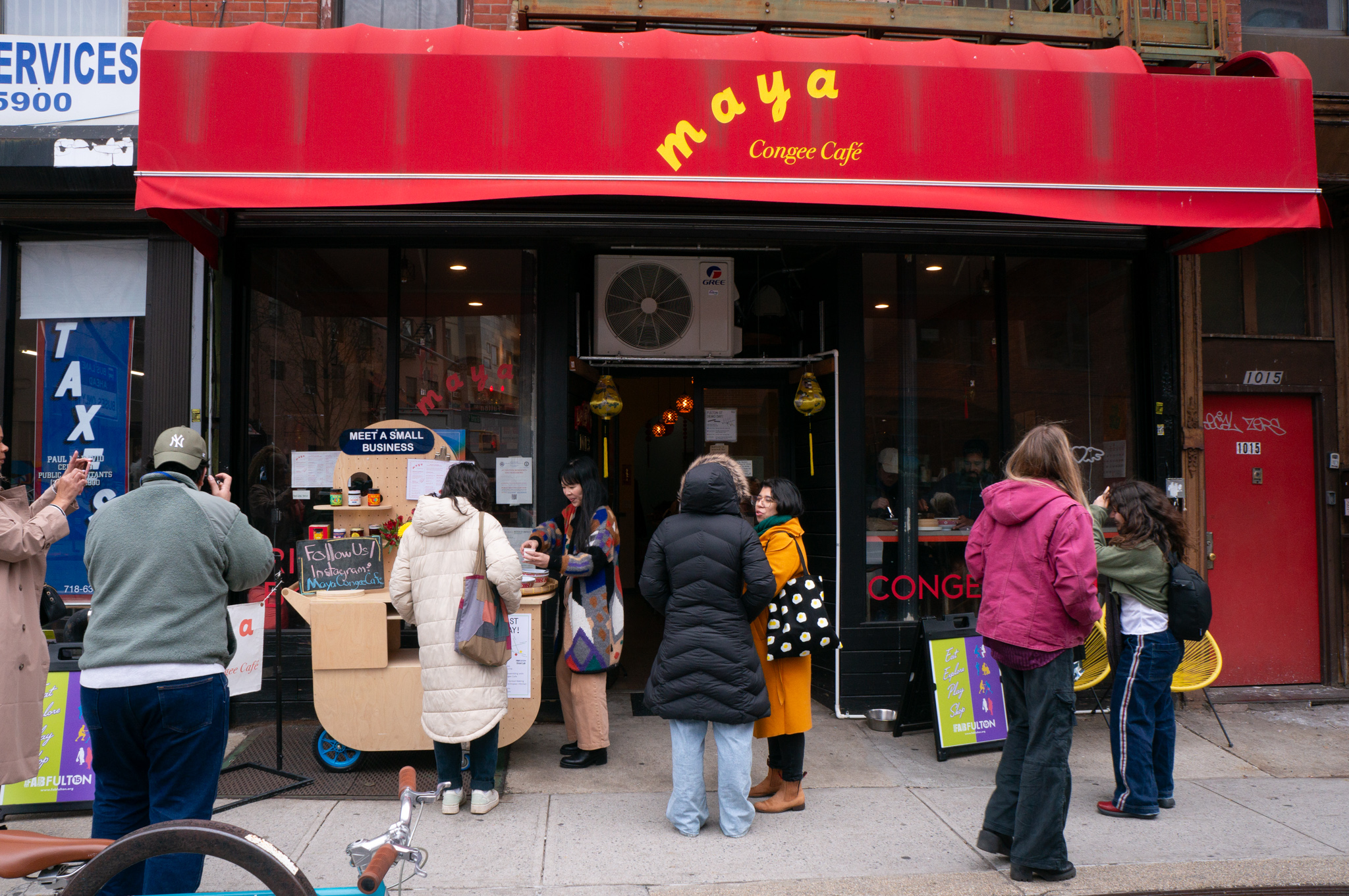 People gathered in front of a storefront "maya congee cafe"