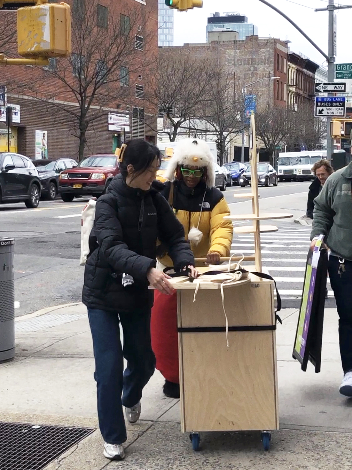 People rolling down a wooden cart down the street.