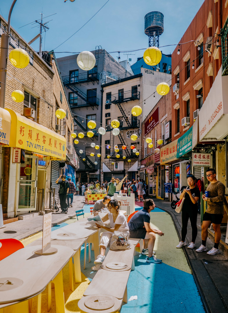 People sitting around one big table on the street of Chinatown in Manhattan.