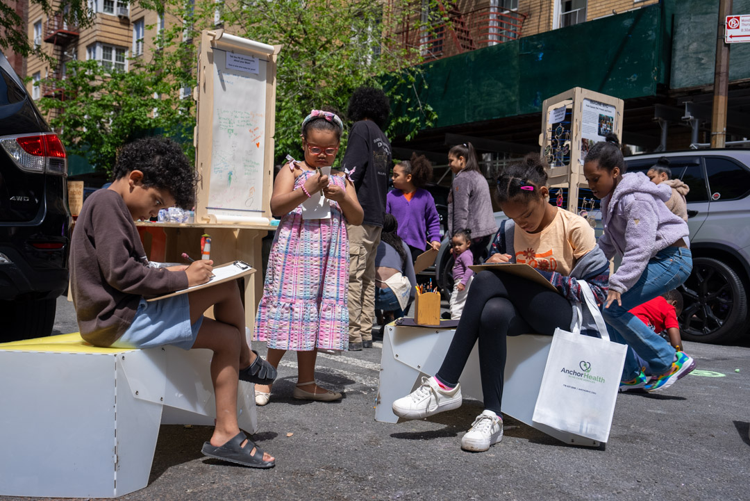 Kids drawing and writing things on clipboard on the street.
