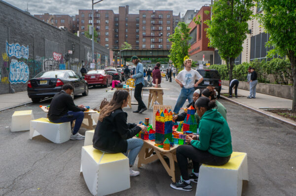 A view of teenagers playing with colorful lego blocks on the street.