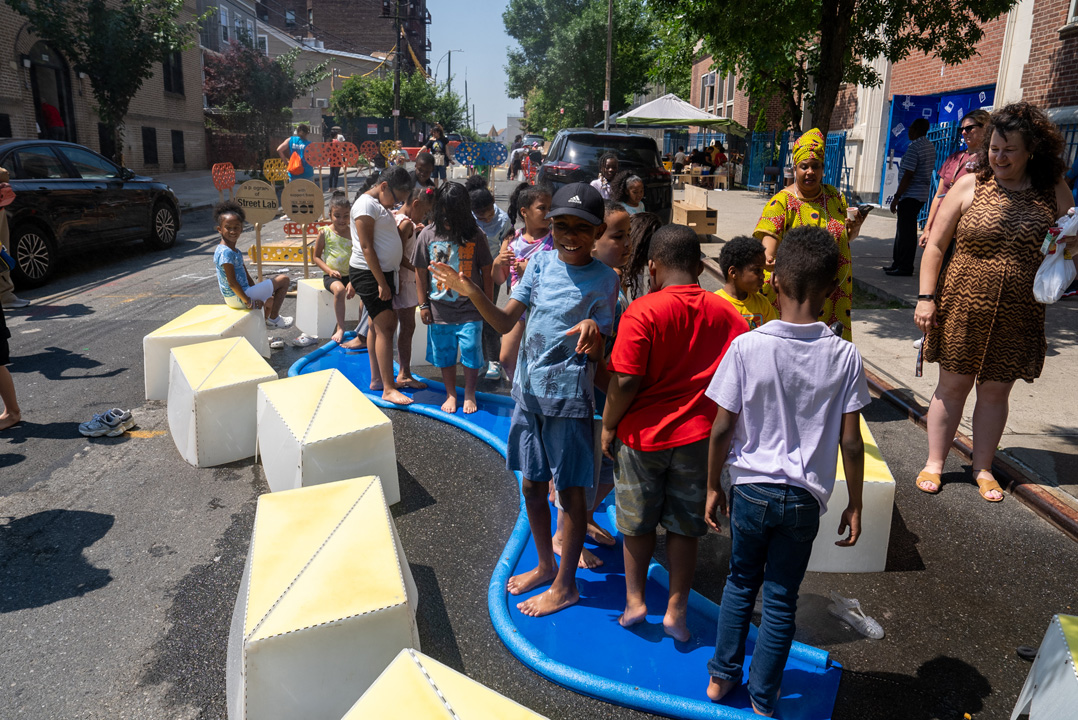 Children playing on the street on top of a blue river-like misting structure.