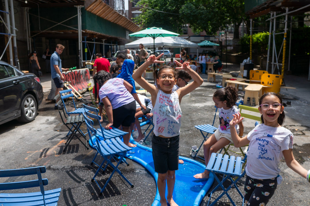 Children playing on the street on top of a blue river-like misting structure.