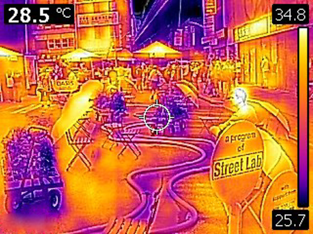 People sitting around a blue, misting river-like structure on the street.
