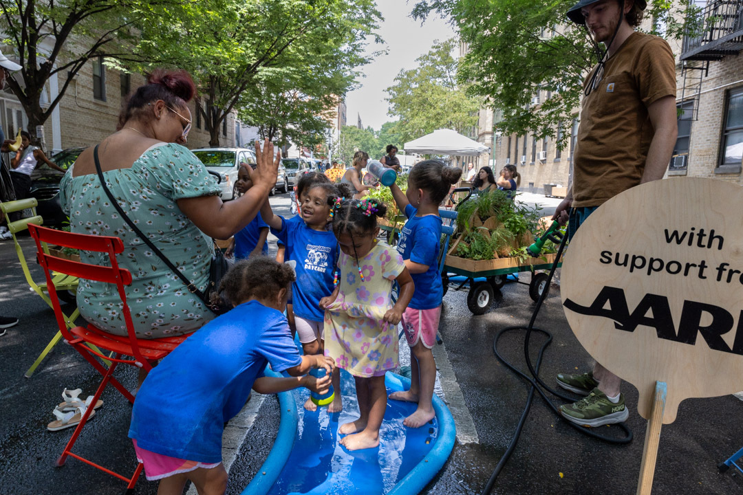 Children playing on a blue, river-like foam structure on the street.