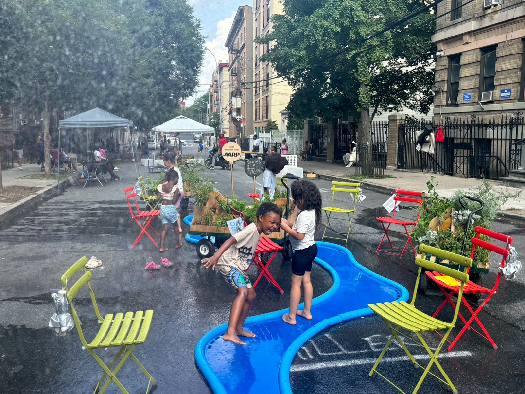 Children playing on the street, on top of a blue, river-like foam structure.