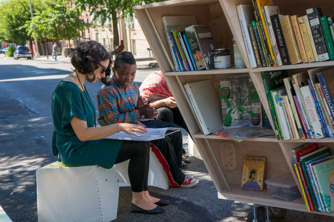 Teenagers and children looking (reading) a picture book together on the street of NYC.