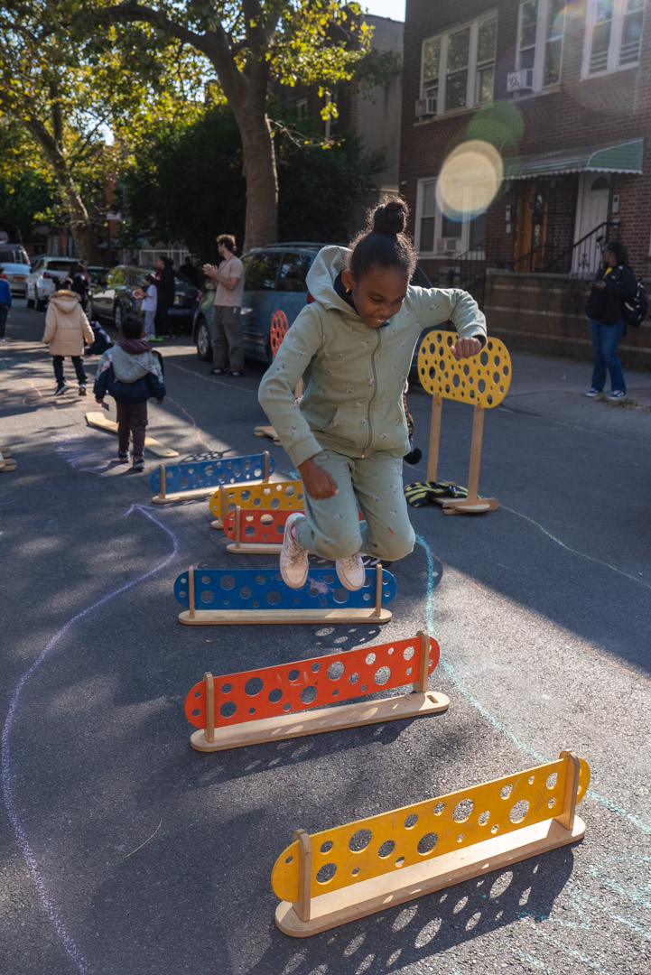 A child and an adult playing with magnatiles on the street.