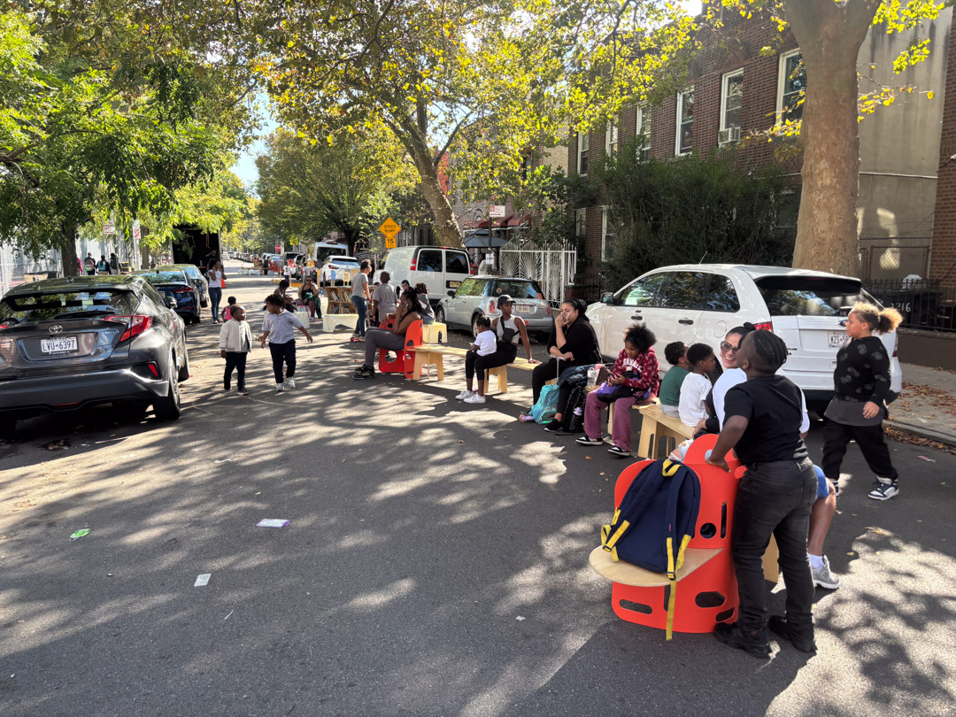 A child and an adult playing with magnatiles on the street.