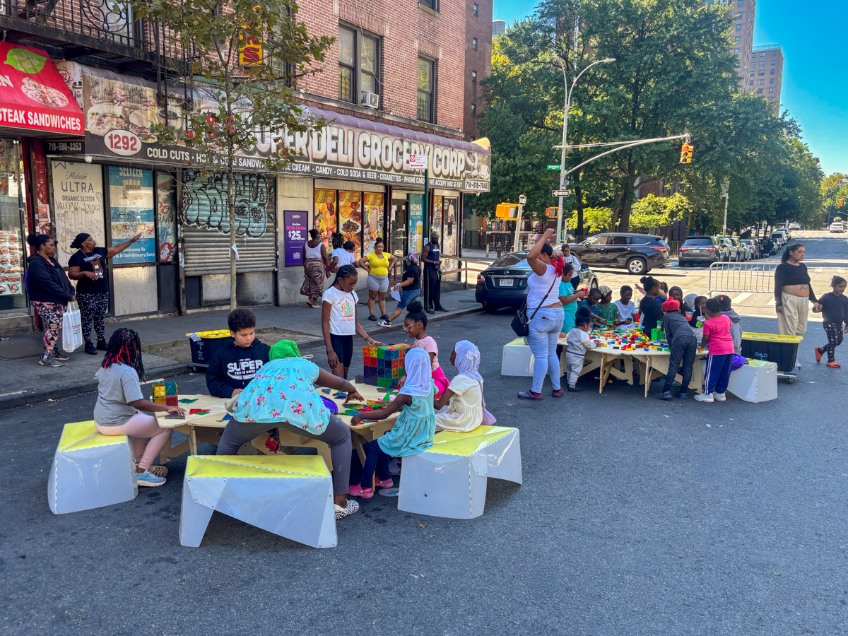 People spending time on the street; a wooden reading cart in the foreground.