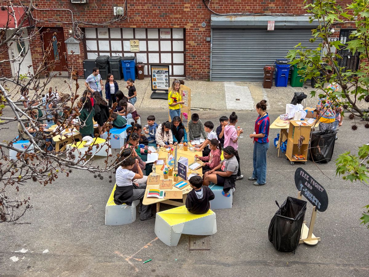 Adults and children writing things on the table on a street.